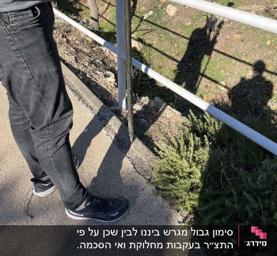 אדם עומד ליד מעקה עם צל על הקרקע